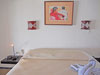 Master bedroom has king-sized bed, ceiling fan and lovely, original artwork.